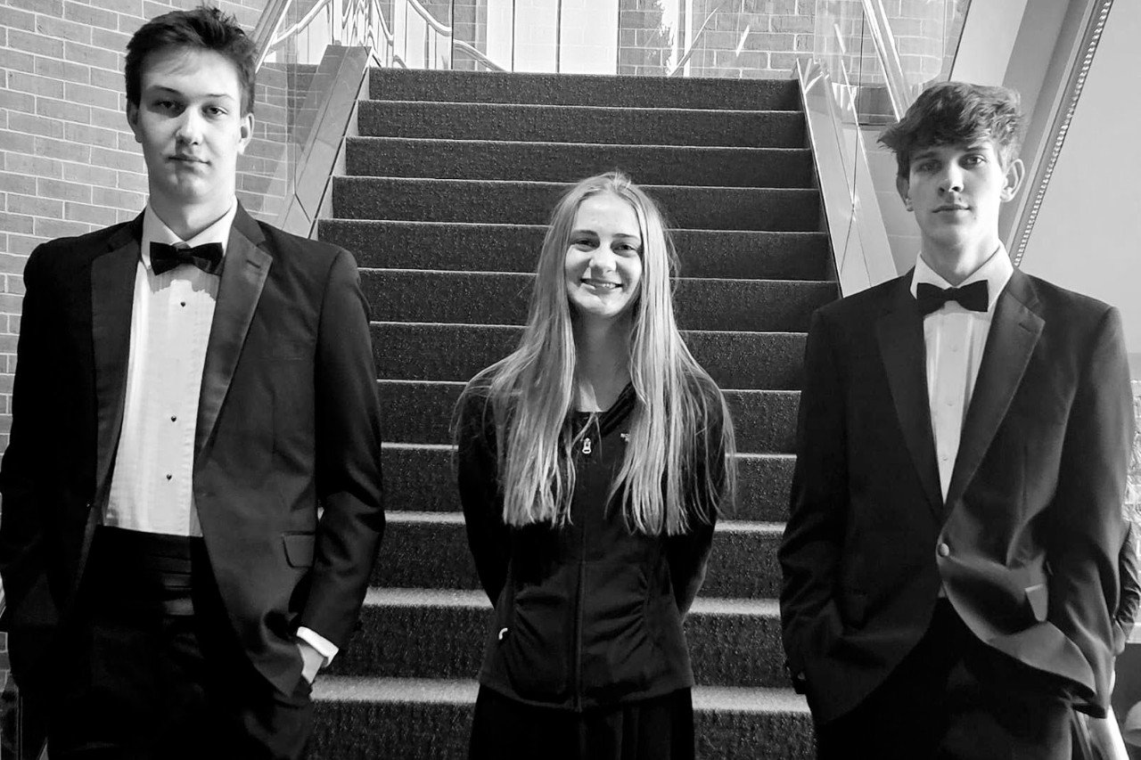 Three students standing in hallway